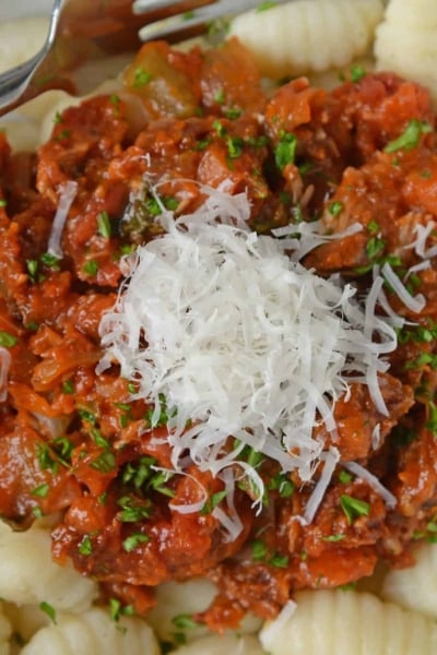 Slow Cooker Ragu uses a blend of 7 vegetables with shredded pork and flavorful spices to make a hearty and delicious ragu sauce. Serve over pasta. Also freezer friendly! #slowcookerragu #slowcookerrecipes www.savoryexperiments.com