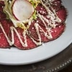 Close up of Beef Tenderloin Carpaccio salad topped with dijon lime dressing