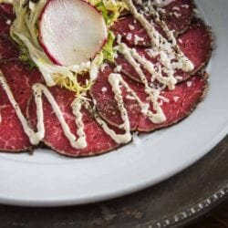 Close up of Beef Tenderloin Carpaccio salad topped with dijon lime dressing