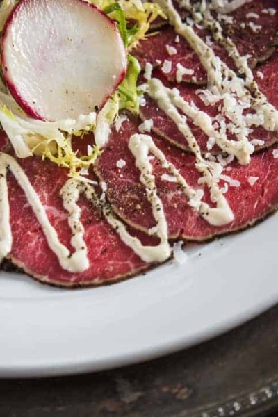 Close up of Beef Tenderloin Carpaccio salad topped with dijon lime dressing