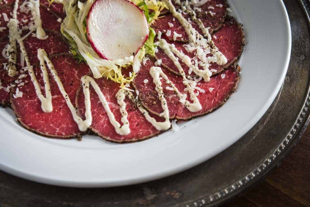 Learn how to make this Beef Tenderloin Carpaccio at home with a tangy side sauce! It's a simple and elegant dish that can be added to salads or other appetizers! #beefcarpacio www.savoryexperiments.com