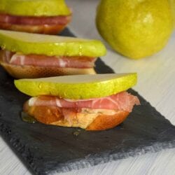 Prosciutto, Pear, and Brie Crostinis fit the bill for any party with tender prosciutto draped over warm brie and topped with a slice of pear and honey. #prosciutto #briecrostinis #crostinis www.savoryexperiments.com