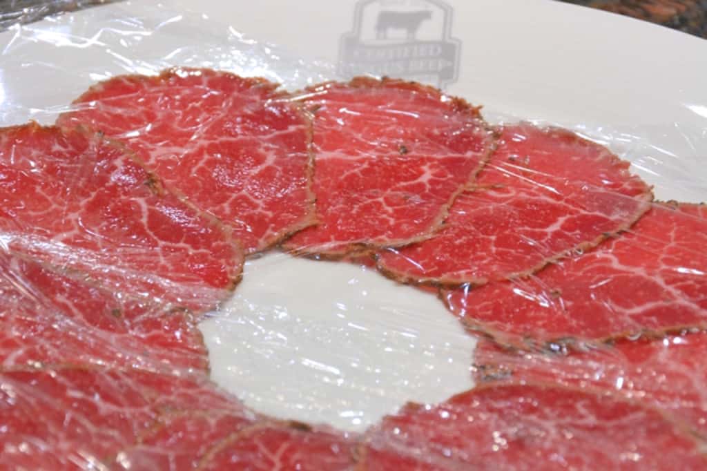 beef carpaccio on a plate with plastic wrap 
