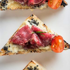Beef Carpaccio Crostini are thinly sliced pieces of beef with garlic aioli, black sea salt and fresh rosemary with tomato. The perfect party appetizer. #beefcarpaccio #crostinirecipes www.savoryexperiments.com