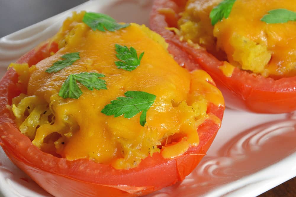 Spaghetti Squash Stuffed Tomatoes are juicy hallowed out tomatoes filled with spaghetti squash and topped with gooey cheddar cheese. The perfect low carb side dish! #lowcarbsidedish #tomatorecipes #spaghettisquashrecipes www.savoryexperiments.com