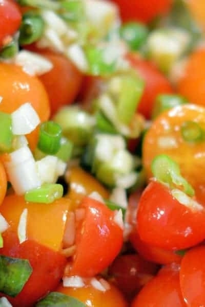 Winter Tomato Salad uses multi-colored cherry tomatoes, lots of garlic, good olive oil and basil to make a tasty side dish recipe perfect for the winter months. #tomatosalad #tomatosidedishes www.savoryexperiments.com