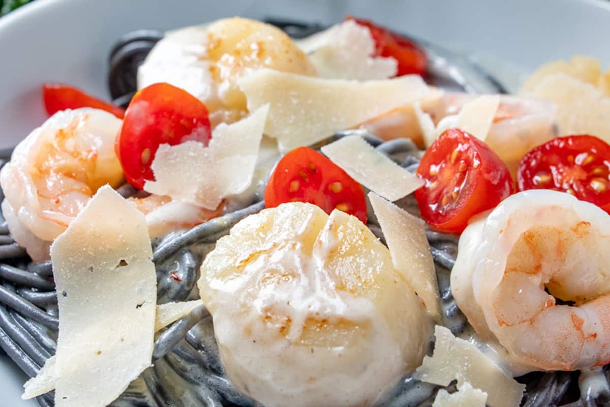 close up of scallop with black pasta