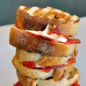 Cheesy Pizza Sandwiches are mini, slider-size grilled cheese sandwiches with mozzarella cheese, tomato jam and pepperoni. Kid friendly and great for parties! #pizzasandwiches www.savoryexperiments.com