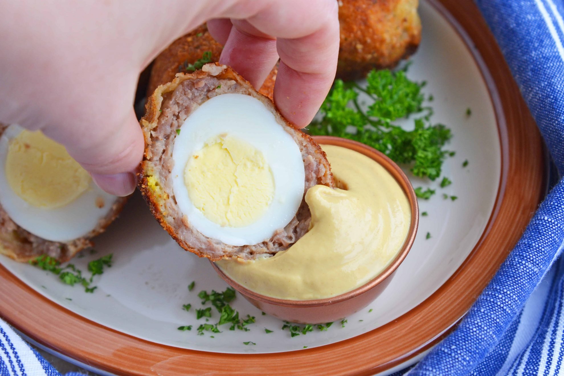 Scotch Egg dipping in Dijon mustard