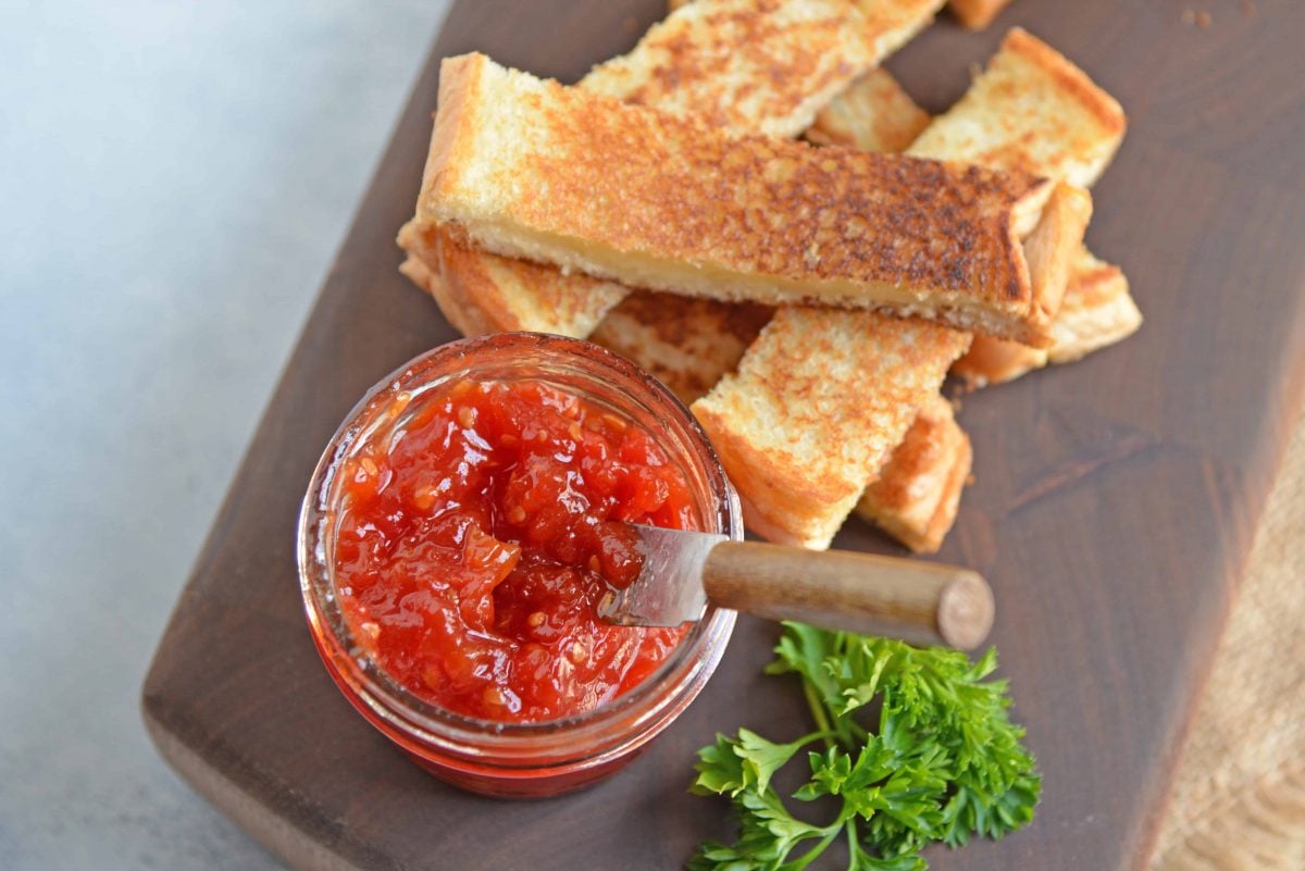 Tangy and sweet, tomato jam is excellent on everything from grilled cheese to deviled eggs, hamburgers and charcuterie boards. #tomatojam #homemadejamrecipe www.savoryexperiments.com 