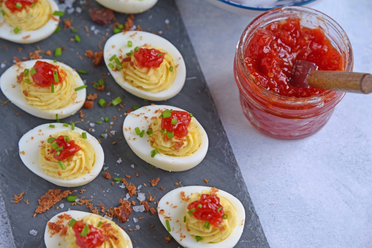 Tomato Jam Deviled Eggs use sweet tomato jam with tangy horseradish in a devilishly creamy deviled egg filling. Top with chives and serve! #deviledeggs www.savoryexperiments.com