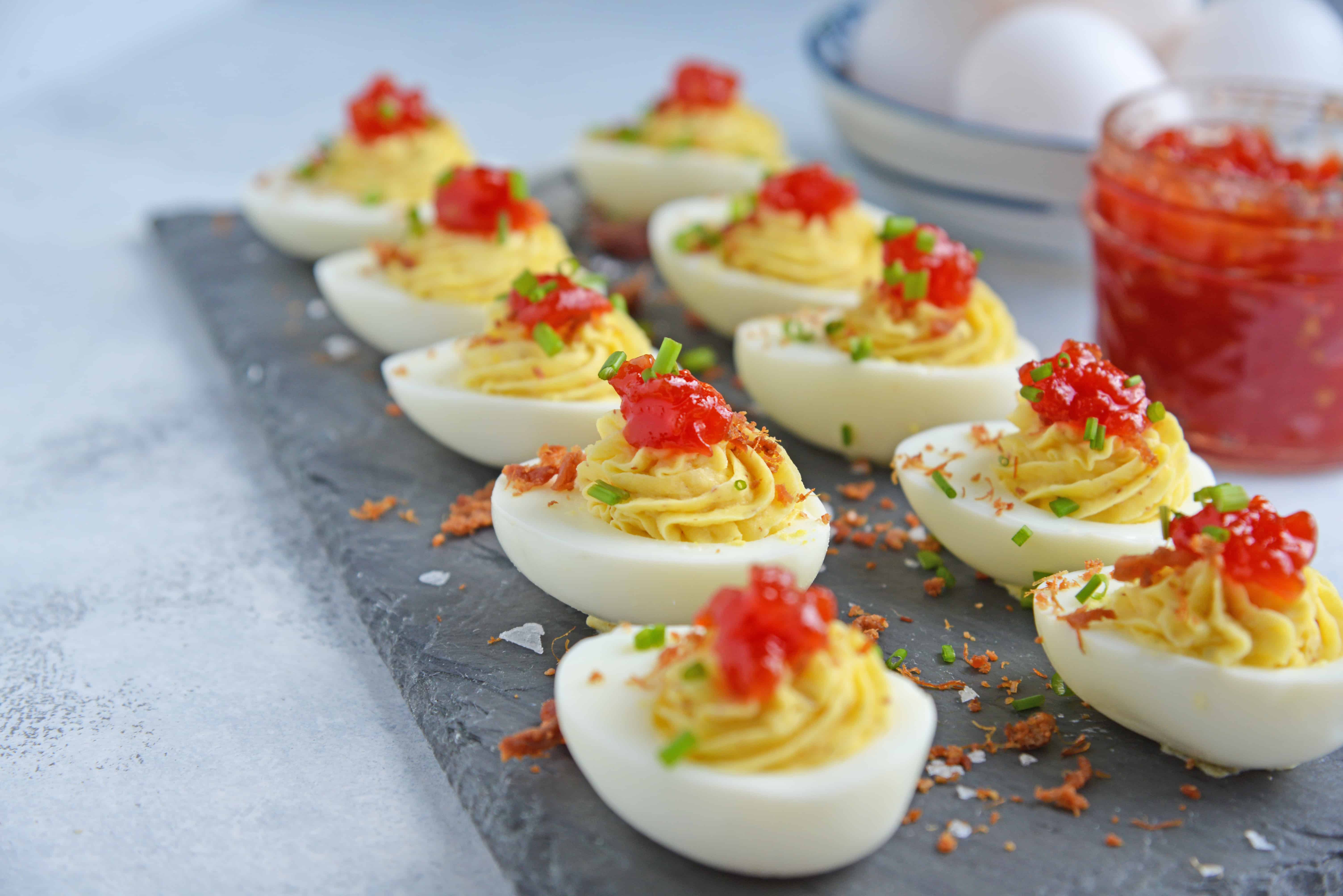 Tomato Jam Deviled Eggs use sweet tomato jam with tangy horseradish in a devilishly creamy deviled egg filling. Top with chives and serve! #deviledeggs www.savoryexperiments.com 