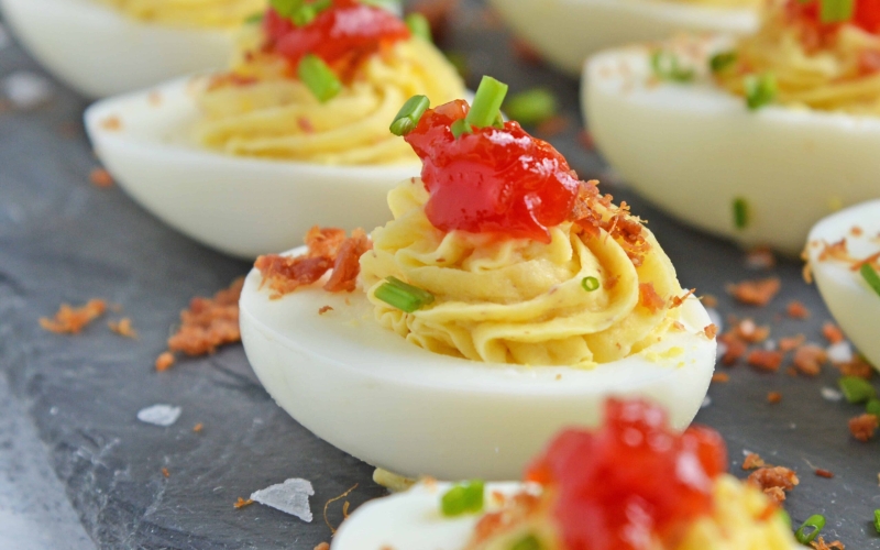 Close up of tomato jam deviled eggs on a slate