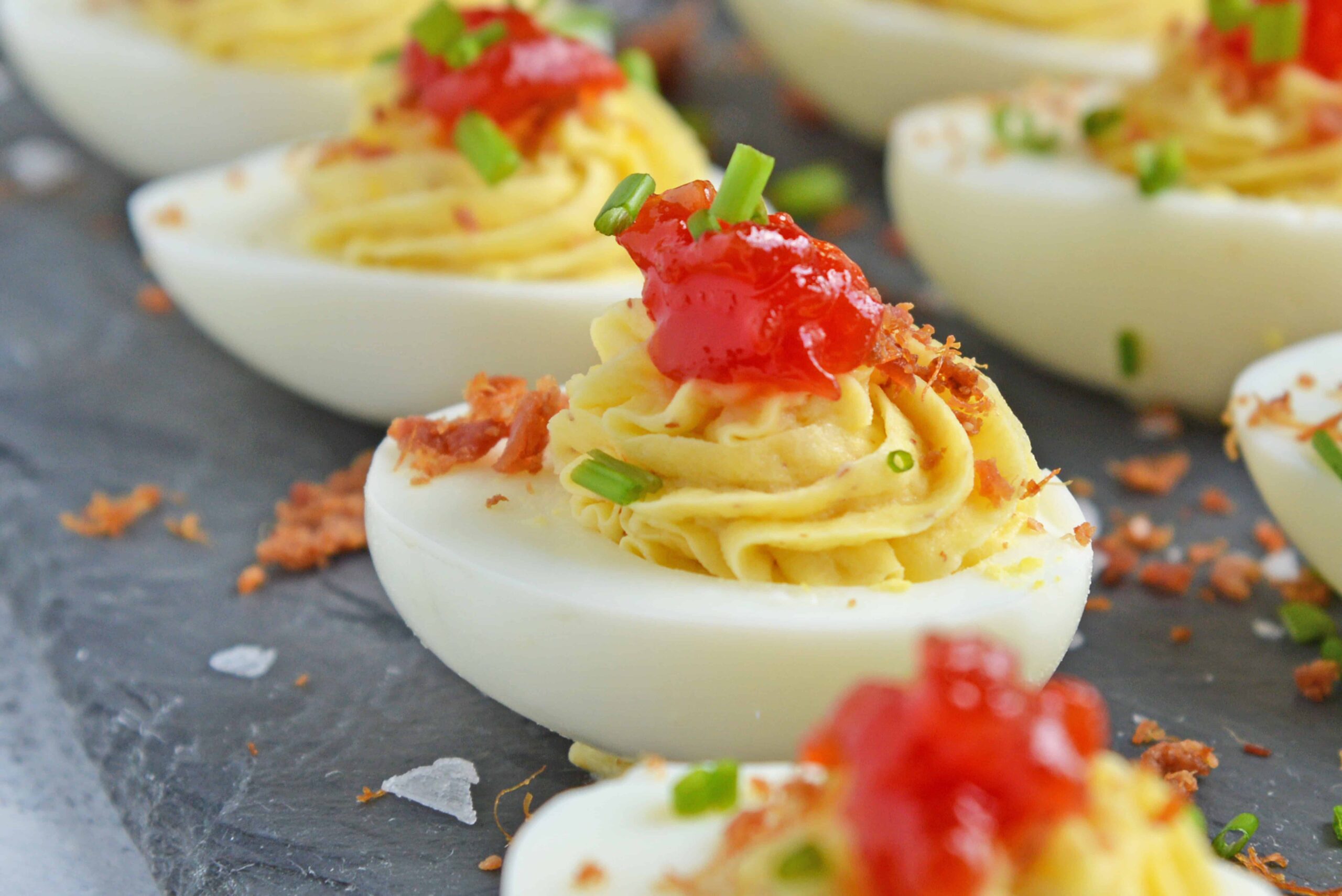 Close up of tomato jam deviled eggs on a slate