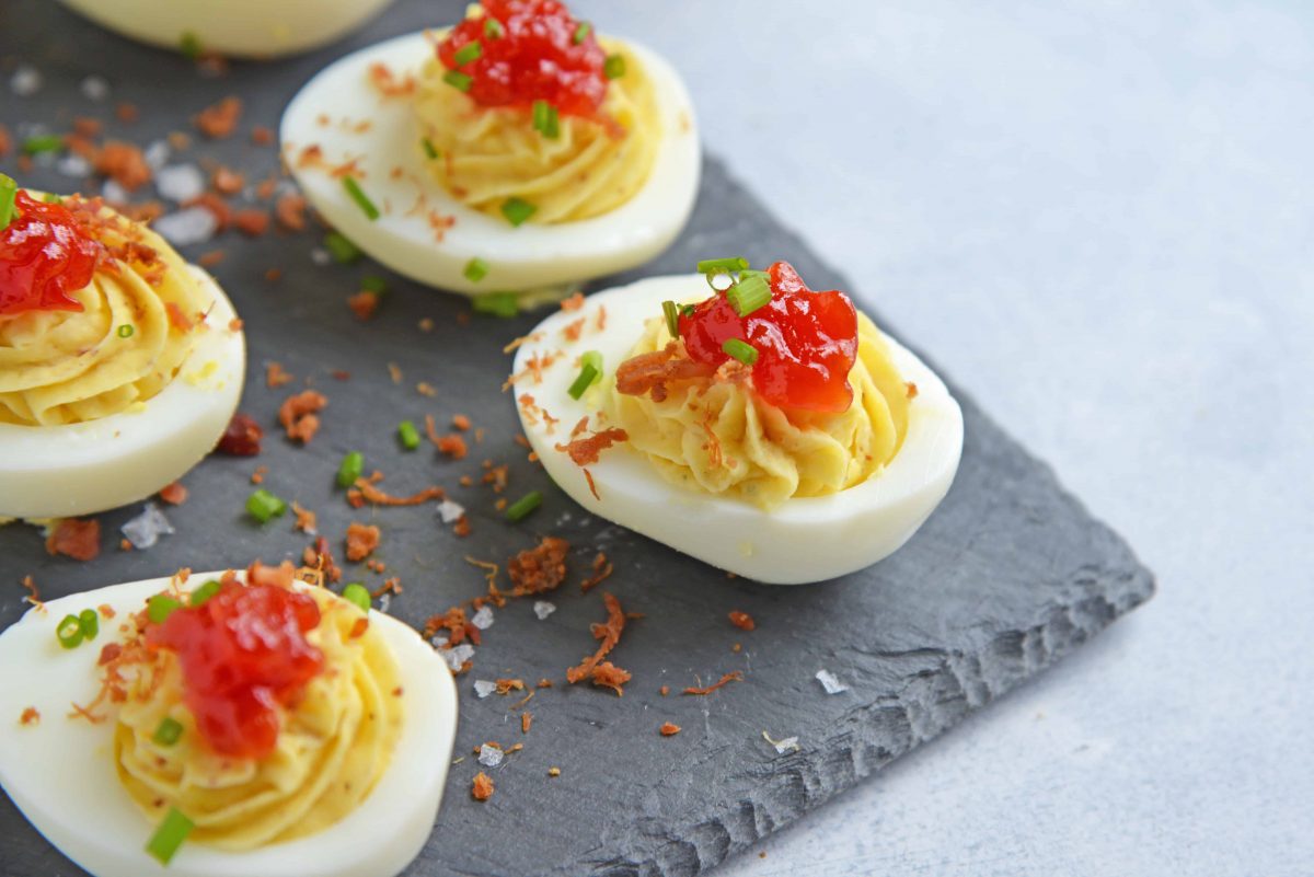 Tomato Jam Deviled Eggs use sweet tomato jam with tangy horseradish in a devilishly creamy deviled egg filling. Top with chives and serve! #deviledeggs www.savoryexperiments.com 