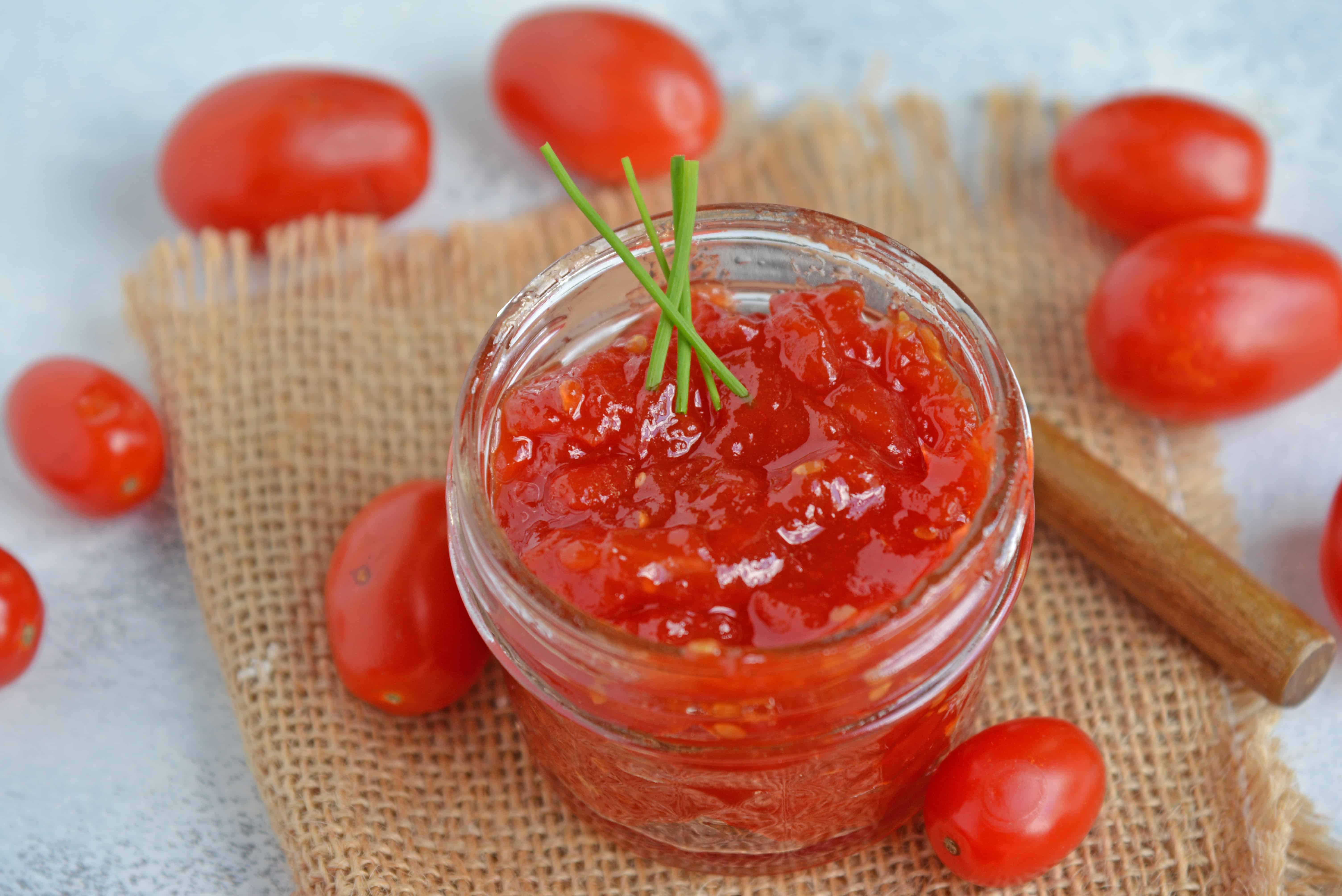 Tangy and sweet, tomato jam is excellent on everything from grilled cheese to deviled eggs, hamburgers and charcuterie boards. #tomatojam #homemadejamrecipe www.savoryexperiments.com