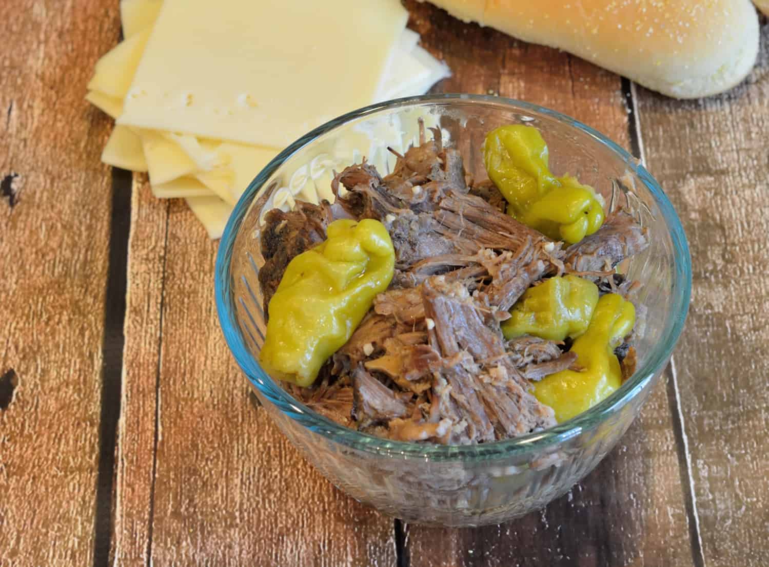 Slow Cooker Italian Beef Hoagies is pot roast cooked in pepperoncini chiles until fork tender, then smothered in cheese and serve on a hoagie roll. Great for parties too! #italianbeefhoagies #mississippipotroast www.savoryexperiments.com