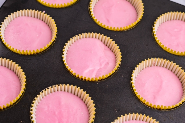pink cupcake batter in liners and muffin tins