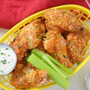 yellow basket of chicken wings with celery and dip