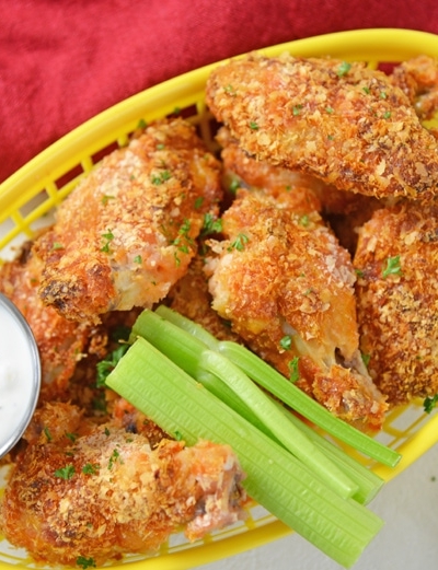 yellow basket of chicken wings with celery and dip