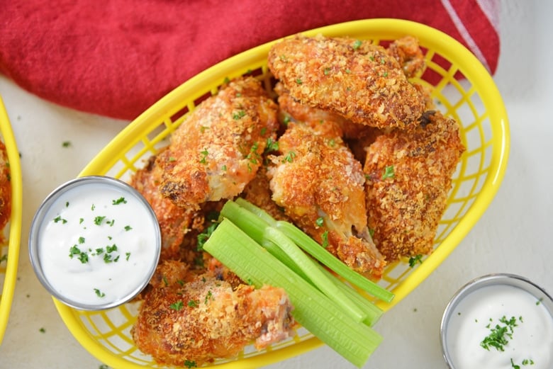 yellow basket of chicken wings with celery and dip