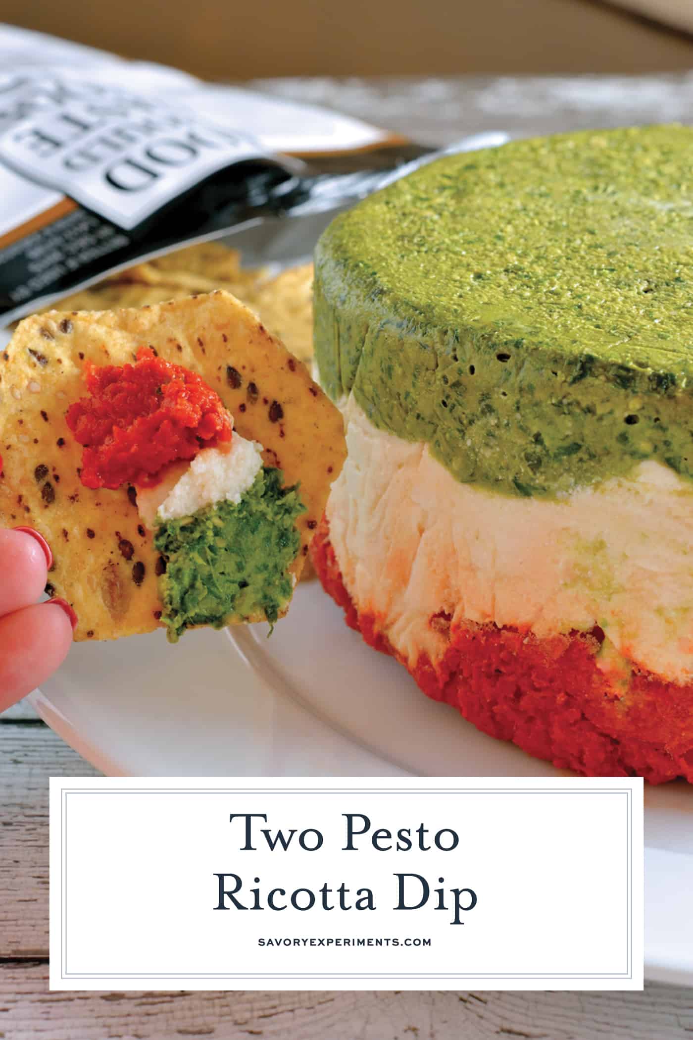 Two Pesto Ricotta Dip combines layers of traditional basil pesto, roasted red pepper and sun dried tomato pesto with ricotta, goat and Parmesan cheese. Chilled in a mold, it is a beautiful red, green and white! #pestodip #ricottadip www.savoryexperiments.com