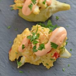 Crab Dip Stuffed Artichoke Hearts takes traditional hot crab dip and bakes in an artichoke heart, topping it with crunchy panko and Sriracha Aioli. #hotcrabdip #artichokerecipes #crabappetizers www.savoryexperiments.com