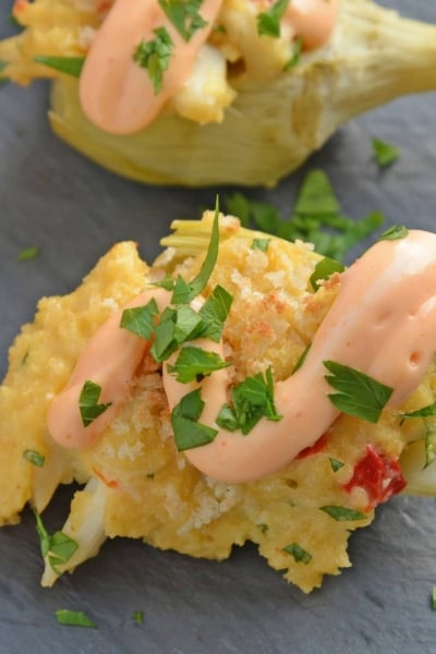 Crab Dip Stuffed Artichoke Hearts takes traditional hot crab dip and bakes in an artichoke heart, topping it with crunchy panko and Sriracha Aioli. #hotcrabdip #artichokerecipes #crabappetizers www.savoryexperiments.com