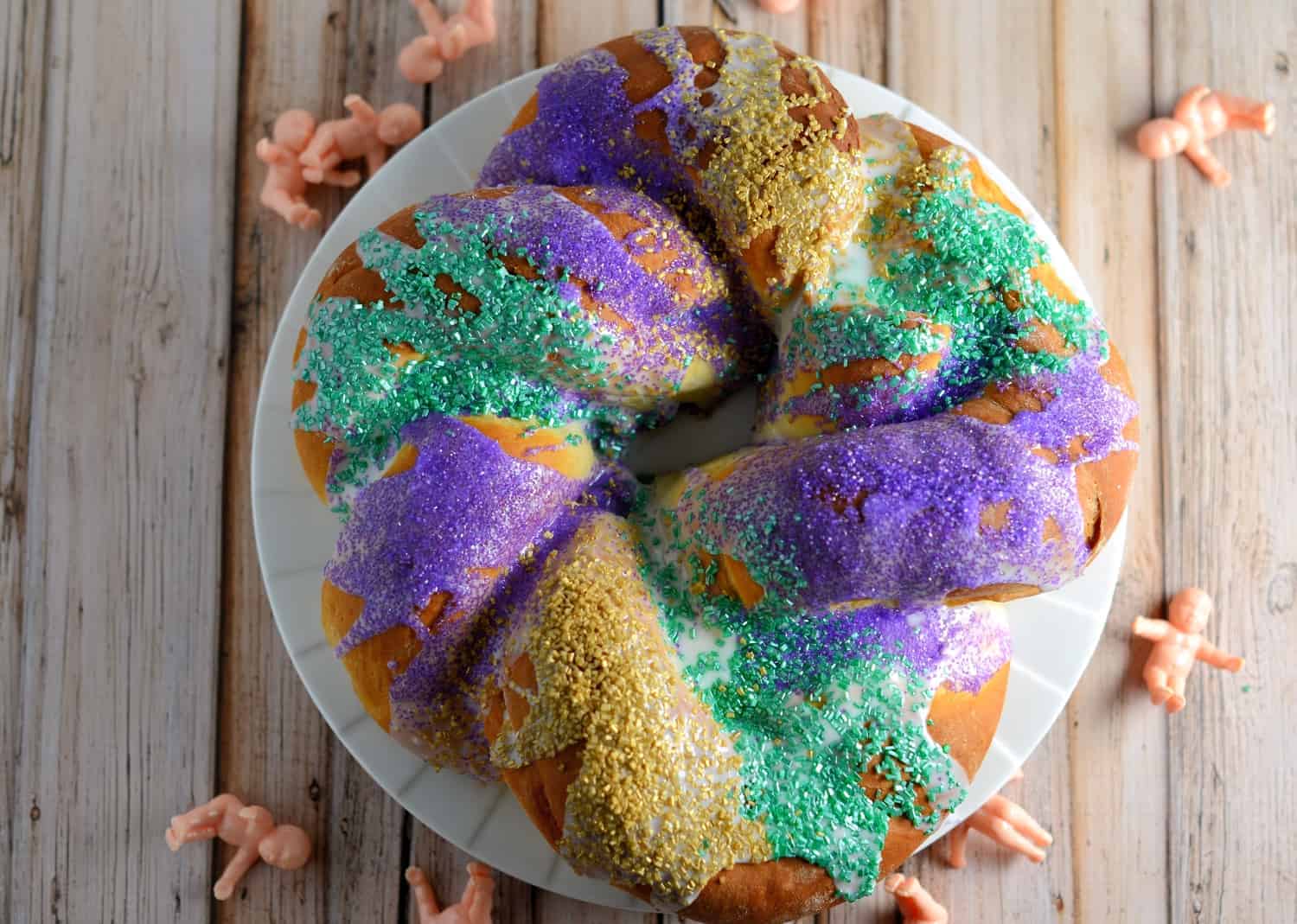 Mardi Gras King Cake Recipe - A giant sweet roll stuffed with brown sugar, raisins and pecans and decorated with icing and purple, green and gold sparkling sugar. Perfect for breakfast or dessert during carnival or on Fat Tuesday!