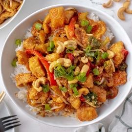 white bowl of cashew chicken over white rice