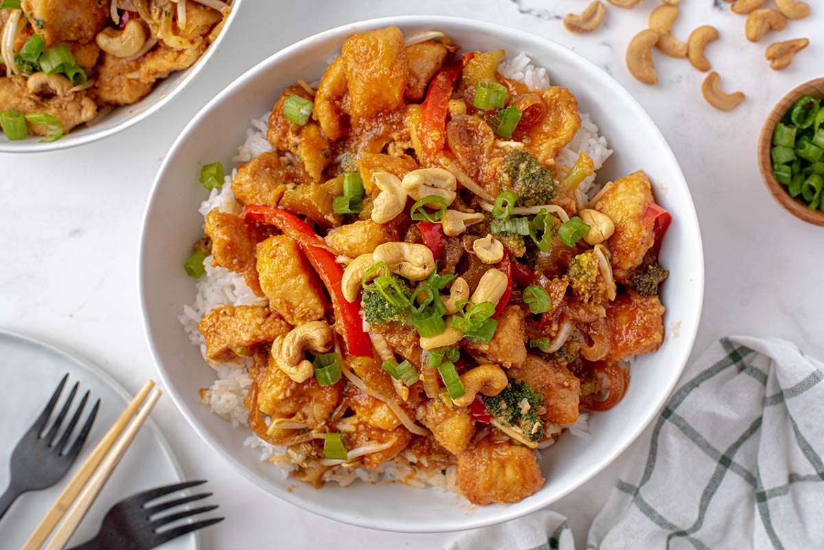 white bowl of cashew chicken over white rice