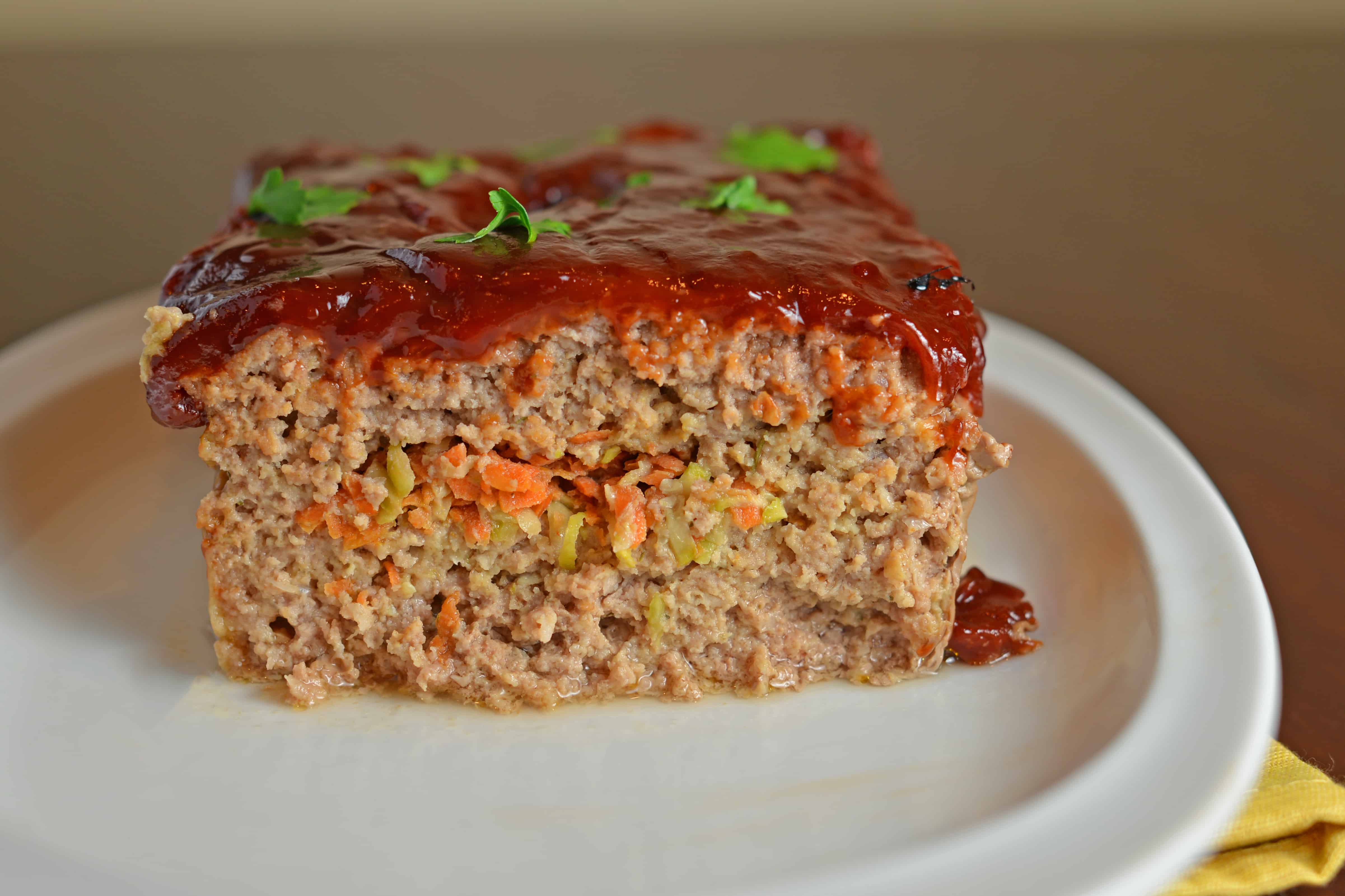 Veggie Stuffed Meatloaf Recipe- The most tender meatloaf ever! Stuffed with carrot and zucchini and topped with a zesty ketchup blend with a special ingredient. Come see what makes this meatloaf one even meatloaf-haters will LOVE! www.savoryexperiments.com