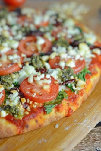 Tomato and Pesto Pizza Recipe - The BEST Homemade Pizza! This is vegetarian and super easy, using 2 types of tomatoes, pesto, mozzarella and feta cheese and toasted pine nuts. Made in a standard kitchen oven! www.savoryexperiments.com