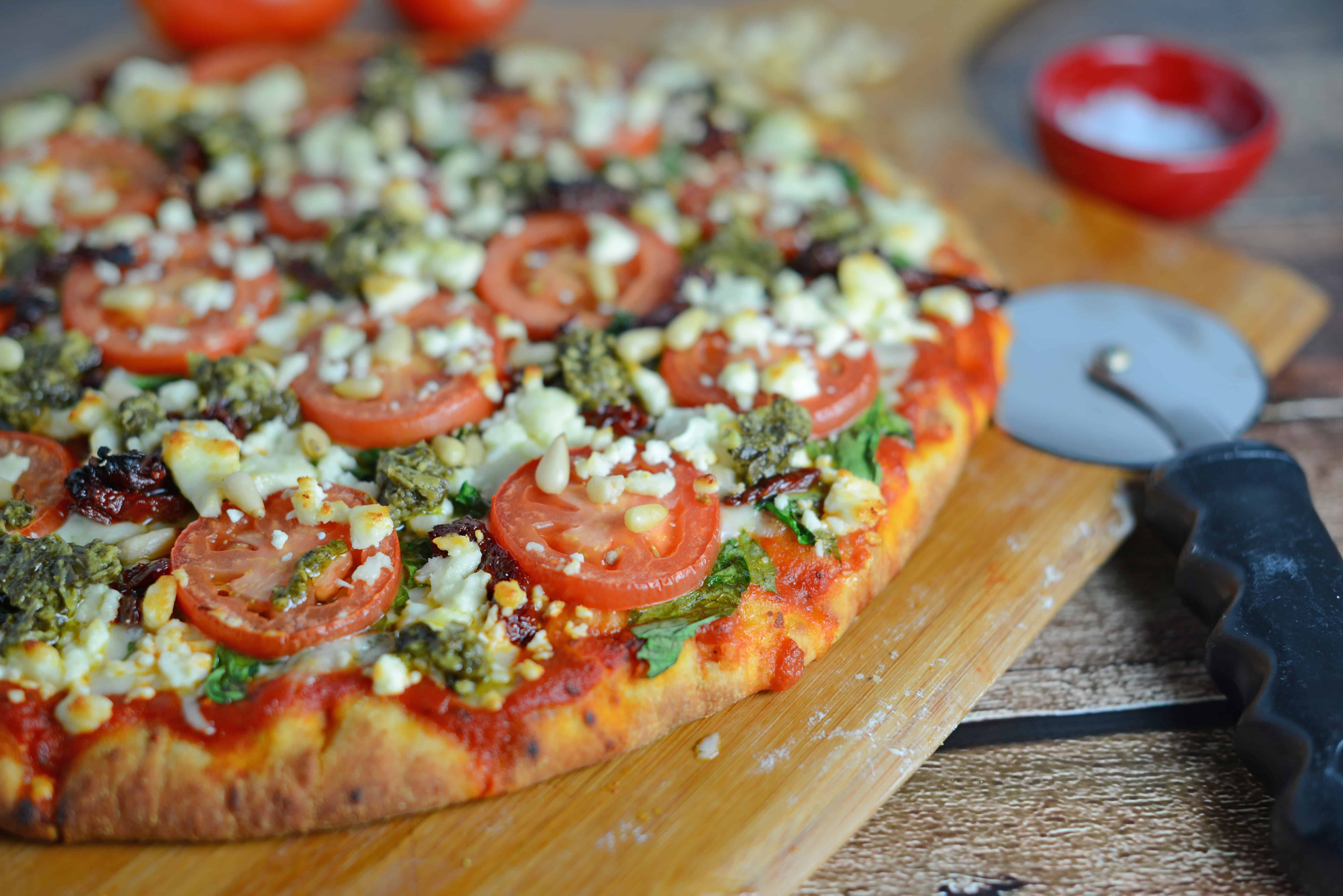 Tomato and Pesto Pizza Recipe - The BEST Homemade Pizza! This is vegetarian and super easy, using 2 types of tomatoes, pesto, mozzarella and feta cheese and toasted pine nuts. Made in a standard kitchen oven! www.savoryexperiments.com