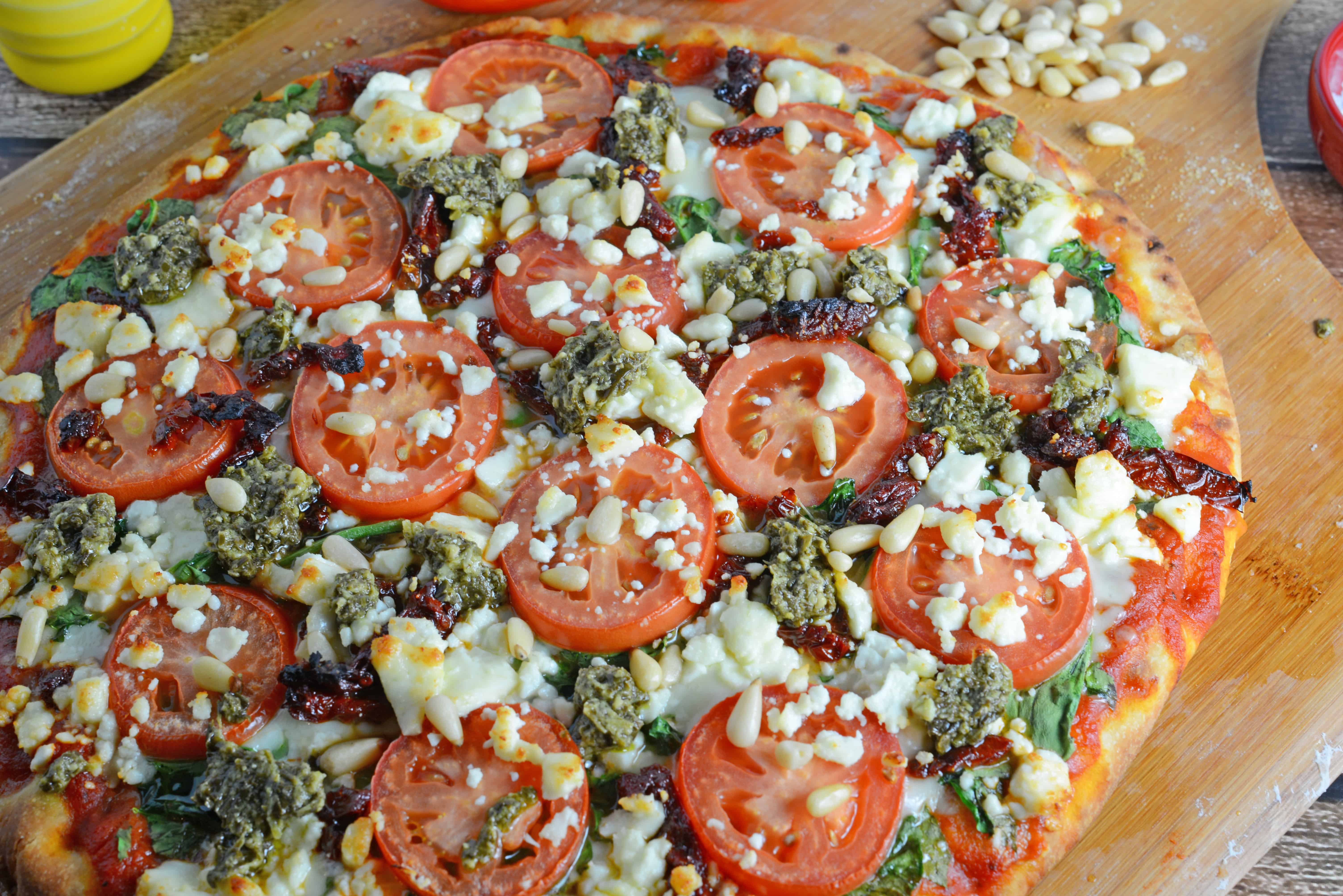 Tomato and Pesto Pizza Recipe - The BEST Homemade Pizza! This is vegetarian and super easy, using 2 types of tomatoes, pesto, mozzarella and feta cheese and toasted pine nuts. Made in a standard kitchen oven! www.savoryexperiments.com