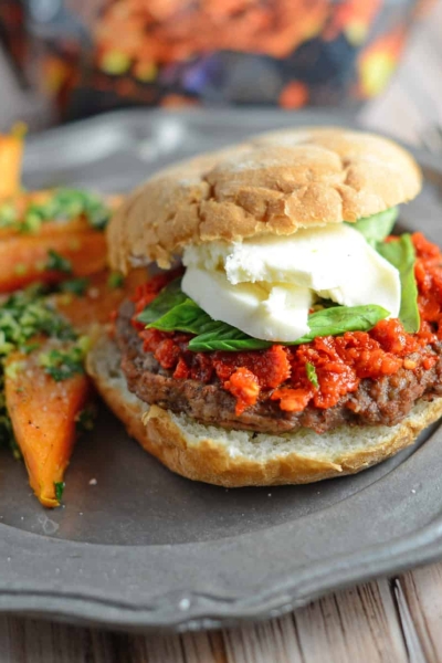 Caprese Burger Recipe - an easy sun dried tomato pesto, fresh basil and mozzarella cheese with your choice of caramelized onions and balsamic reduction. This is the best burger ever! www.savoryexperiments.com