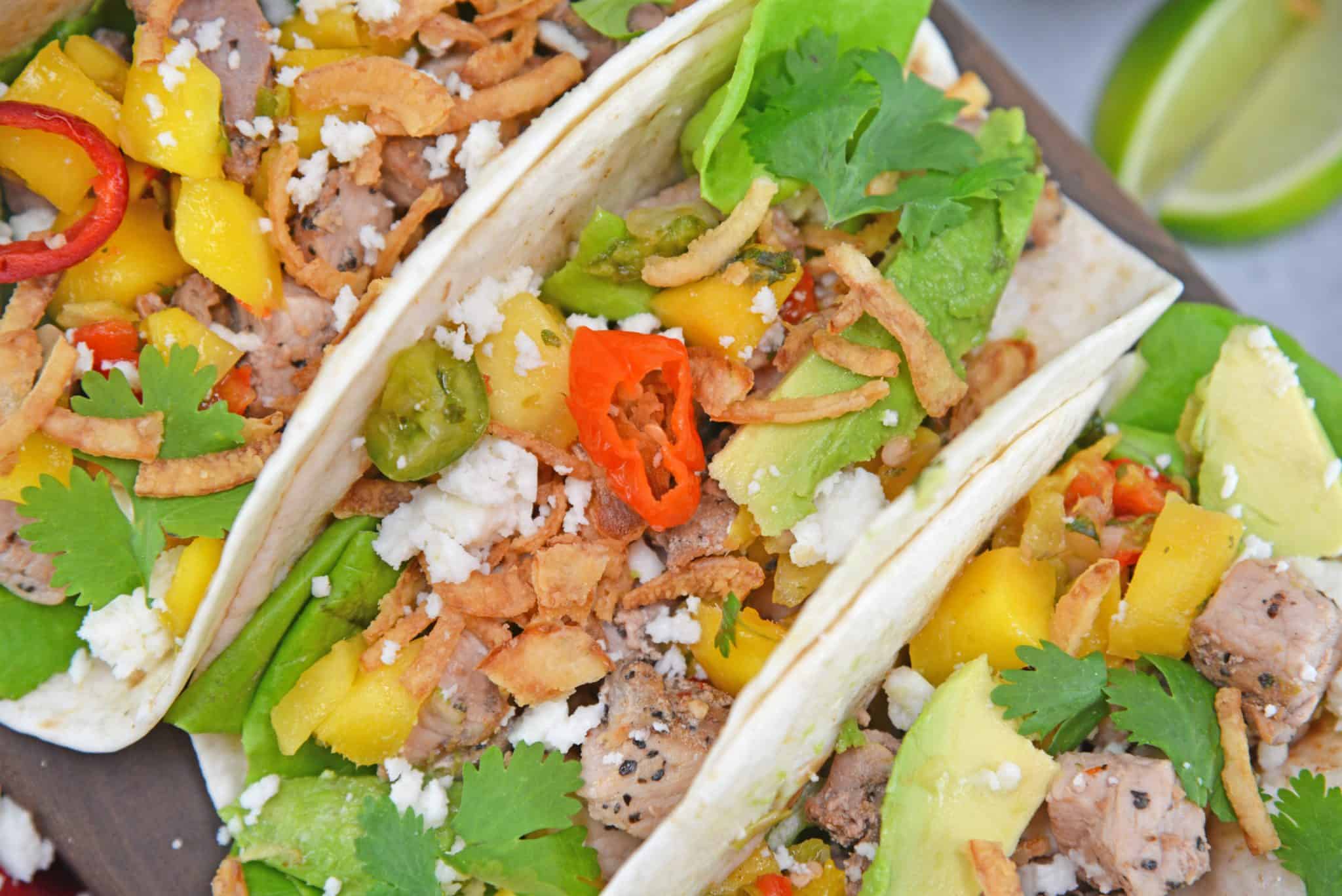 Crispy Pork Tacos are soft tacos filled with mango salsa, cool avocado, crumbly queso fresco, butter lettuce and crispy onion straws.