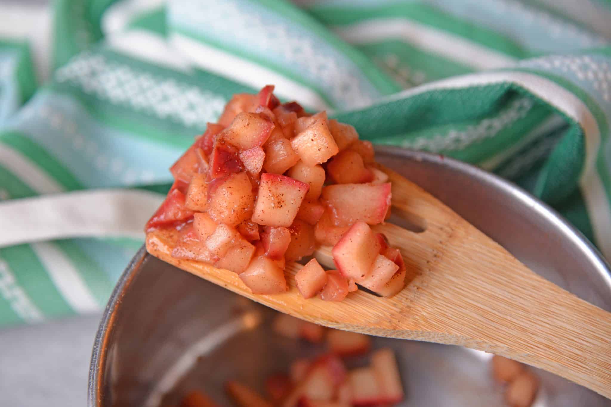 wooden spoon holding cooked apple filling 