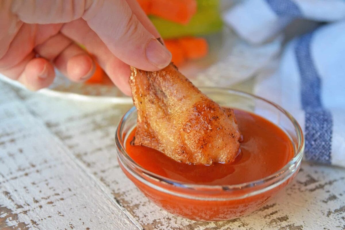 dipping a wing in buffalo sauce 