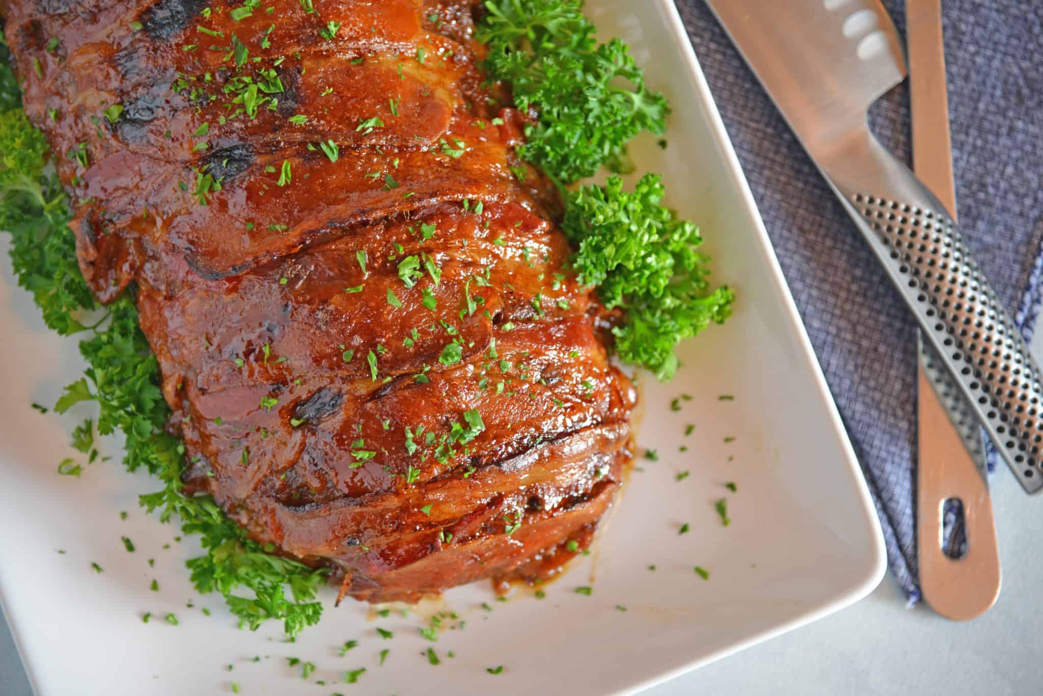 Guinness and Cheddar Meatloaf is packed with vegetables simmered in stout beer and fresh sage topped with crispy bacon and a sweet molasses glaze. #baconwrappedmeatloaf #easymeatloafrecipes www.savoryexperiments.com 