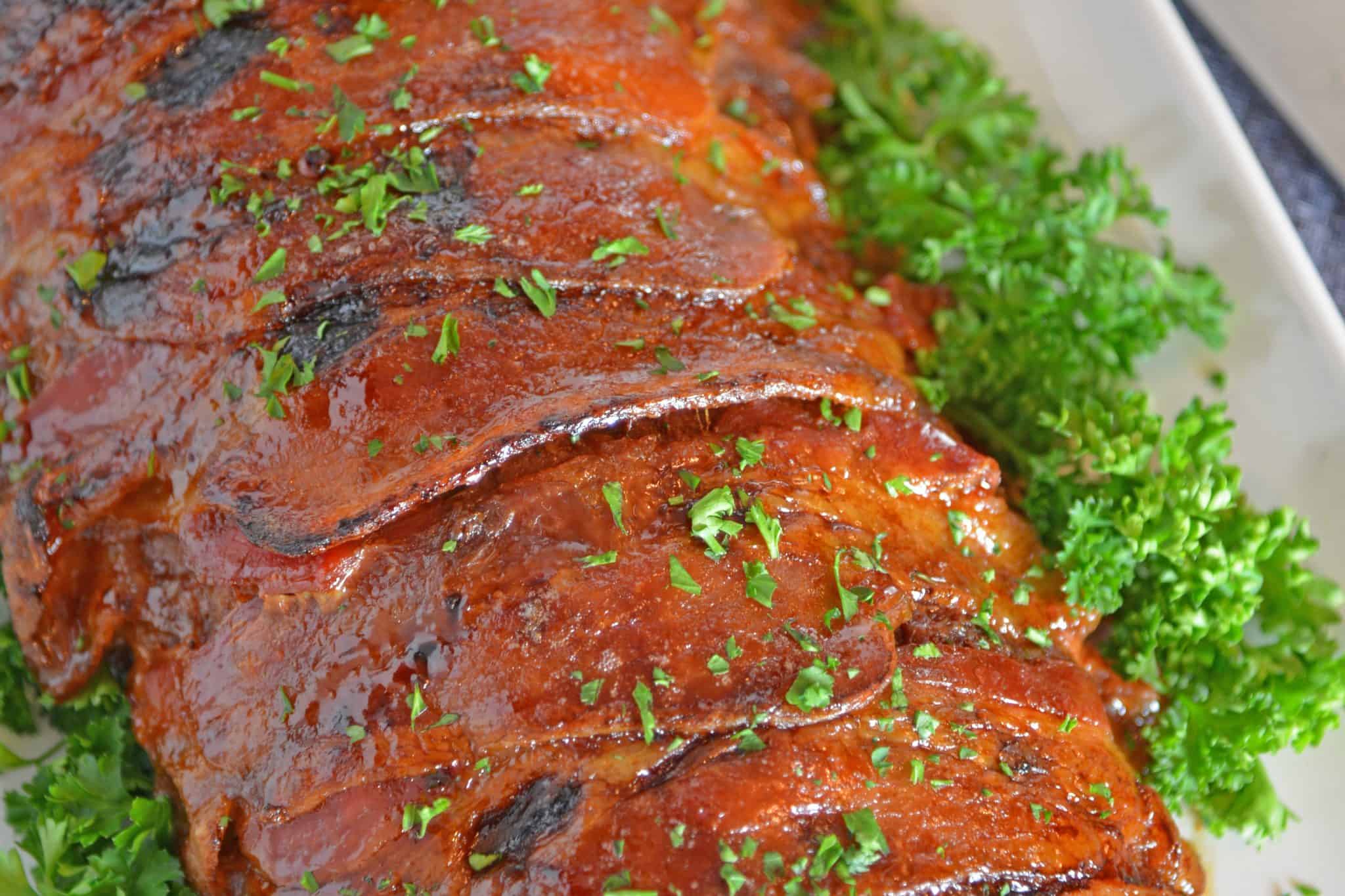 Guinness and Cheddar Meatloaf is packed with vegetables simmered in stout beer and fresh sage topped with crispy bacon and a sweet molasses glaze. #baconwrappedmeatloaf #easymeatloafrecipes www.savoryexperiments.com 