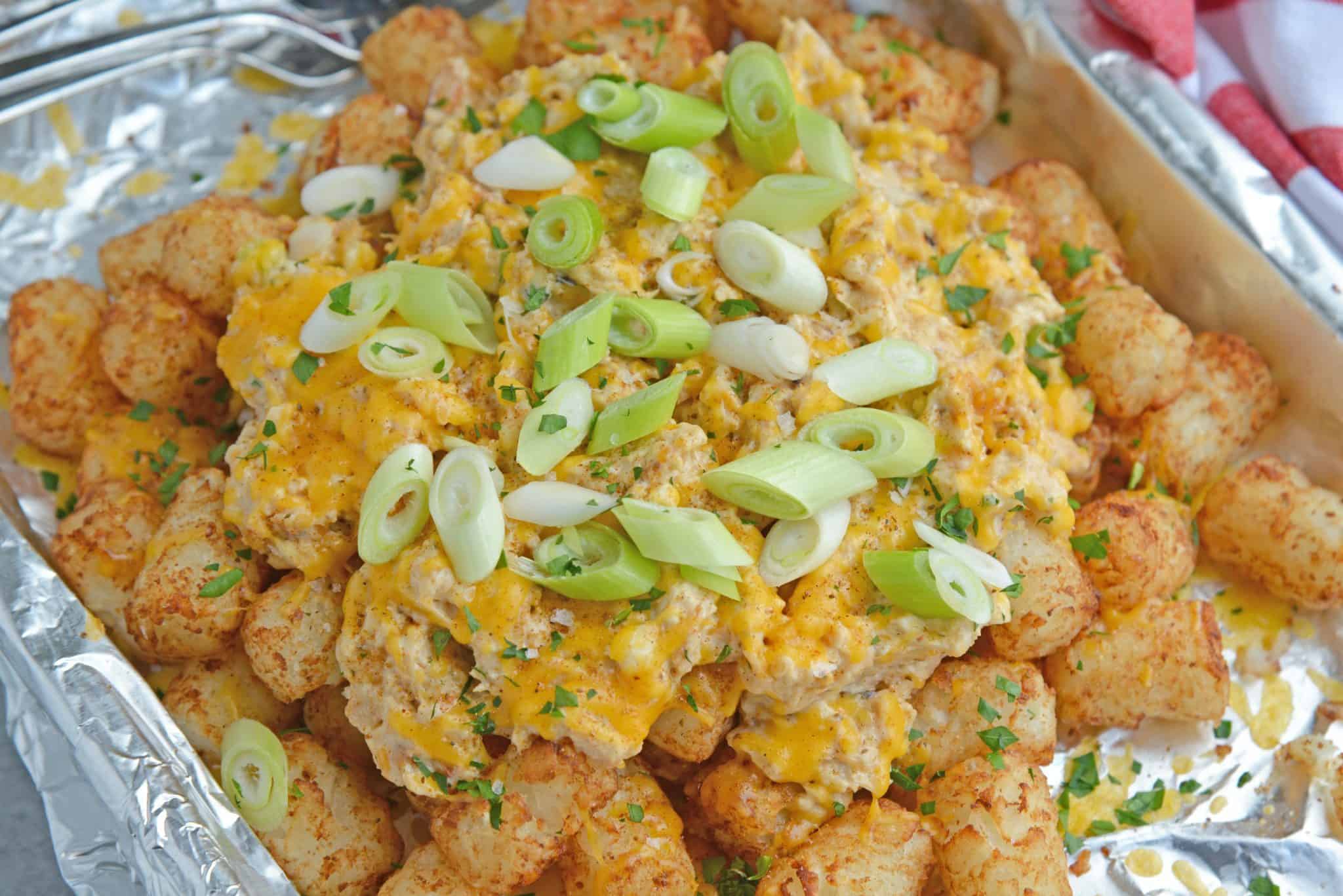 Crabby Totchos are crispy fried tater tots smothered in hot crab dip and topped with melty cheddar cheese. The perfect party appetizer! #tatertots #easyappetizerrecipes www.savoryexperiments.com