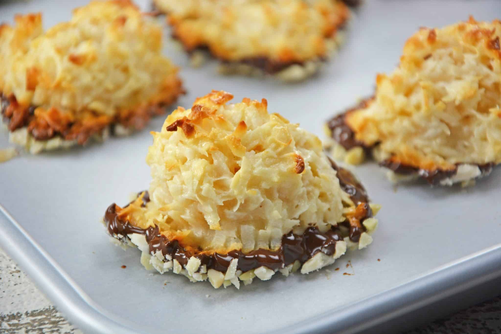 Almond Coconut Macaroons are light, fluffy coconut biscuits dipped in chocolate and almonds. Perfect as a dessert, for tea for as a an afternoon snack. #coconutmacaroons #macaroonsrecipe www.savoryexperiments.com 