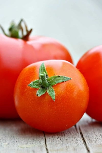 Learn how to peel a tomato in just a minute! Super easy without cooking the tomato. Perfect for sauces, salads and salsas! #howtopeelatomato #tomatoes www.savoryexperiments.com