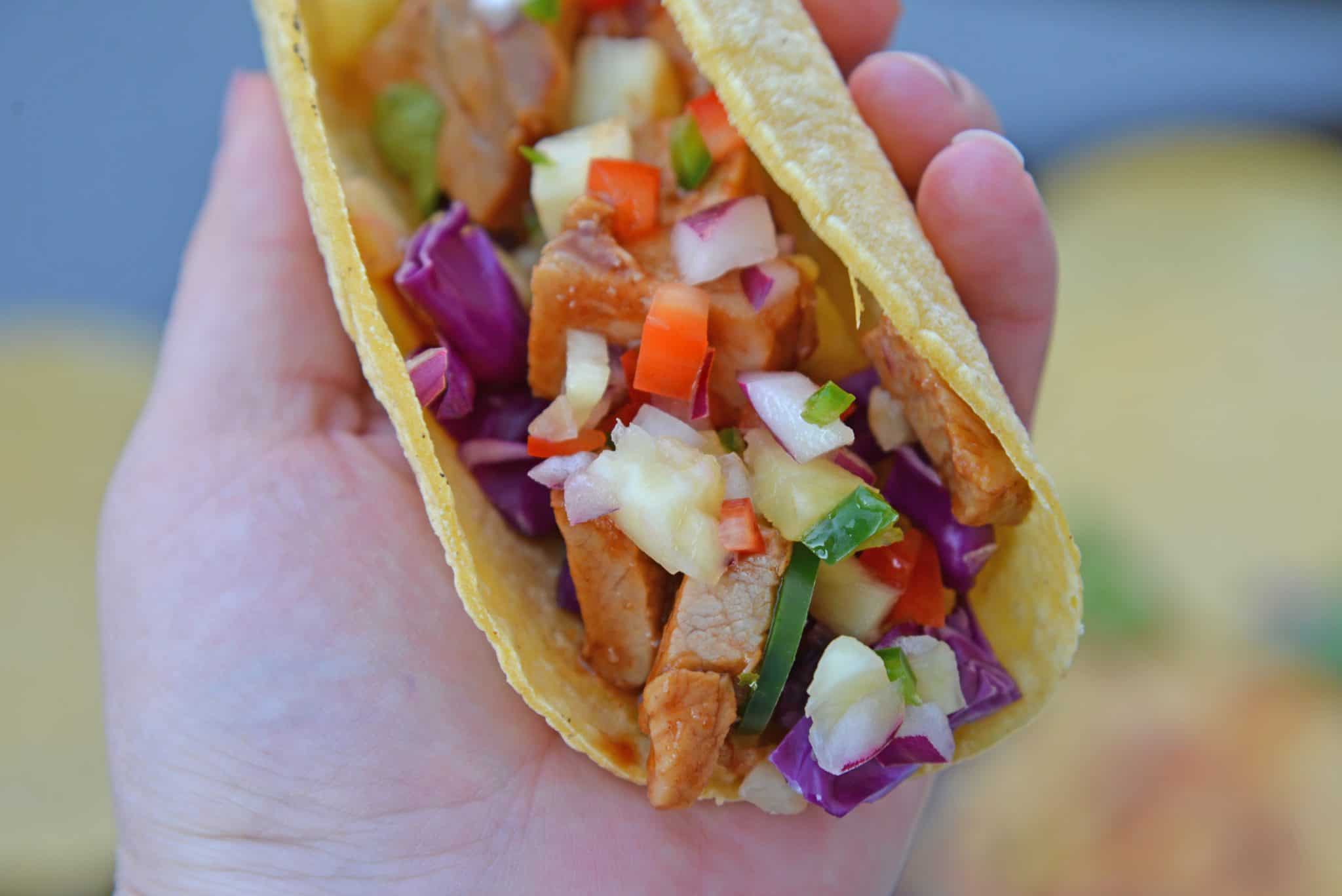 BBQ Pork Tacos are a colorful and easy weeknight dinner. Zesty BBQ sauce paired with sweet and spicy pineapple salsa and crunchy red cabbage. #porktacos #tacotuesday www.savoryexperiments.com