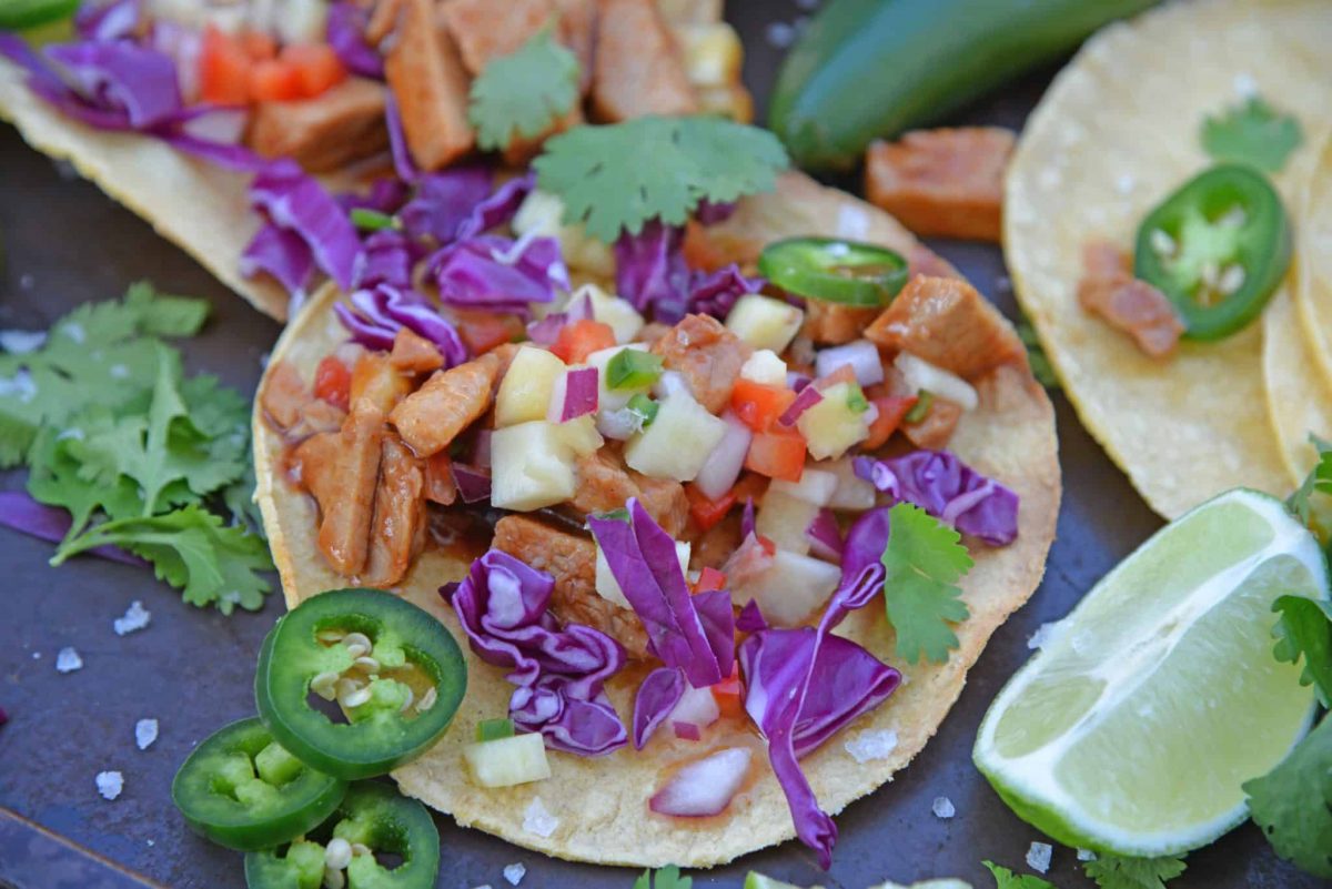 BBQ Pork Tacos are a colorful and easy weeknight dinner. Zesty BBQ sauce paired with sweet and spicy pineapple salsa and crunchy red cabbage. #porktacos #tacotuesday www.savoryexperiments.com