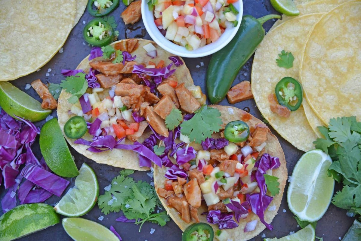 BBQ Pork Tacos are a colorful and easy weeknight dinner. Zesty BBQ sauce paired with sweet and spicy pineapple salsa and crunchy red cabbage. #porktacos #tacotuesday www.savoryexperiments.com