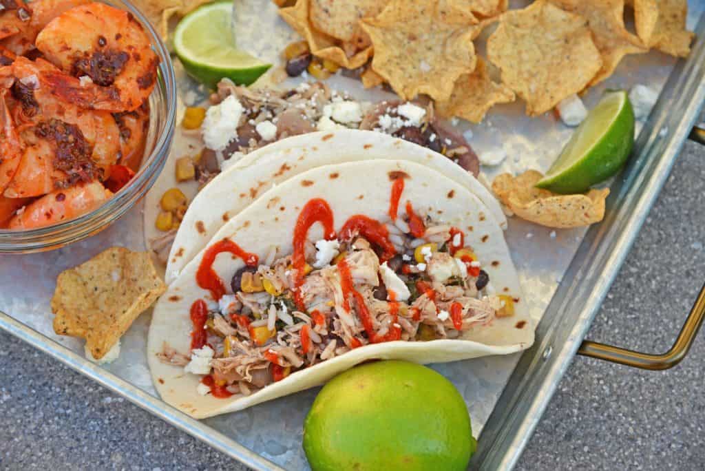 Slow cooker chicken tacos on a silver tray with a lime