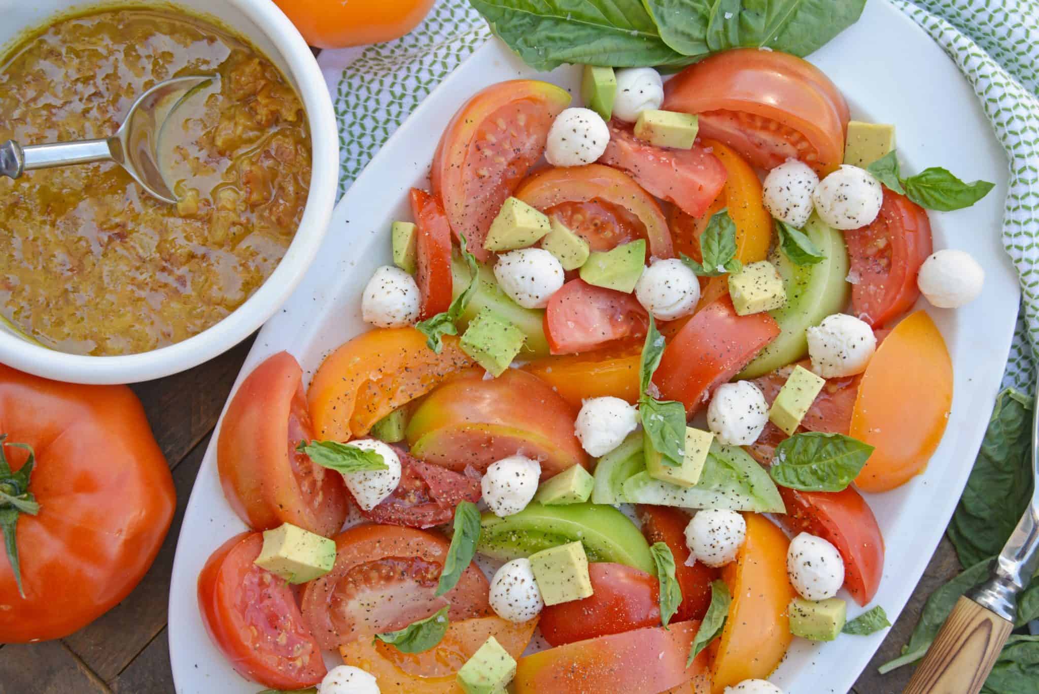 Tomato Salad with Mustard Bacon Dressing is the ultimate summer side dish using lush tomatoes, avocado mozzarella basil. Make it ahead for any party or BBQ. #tomatosalad #tomatorecipes www.savoryexperiments.com