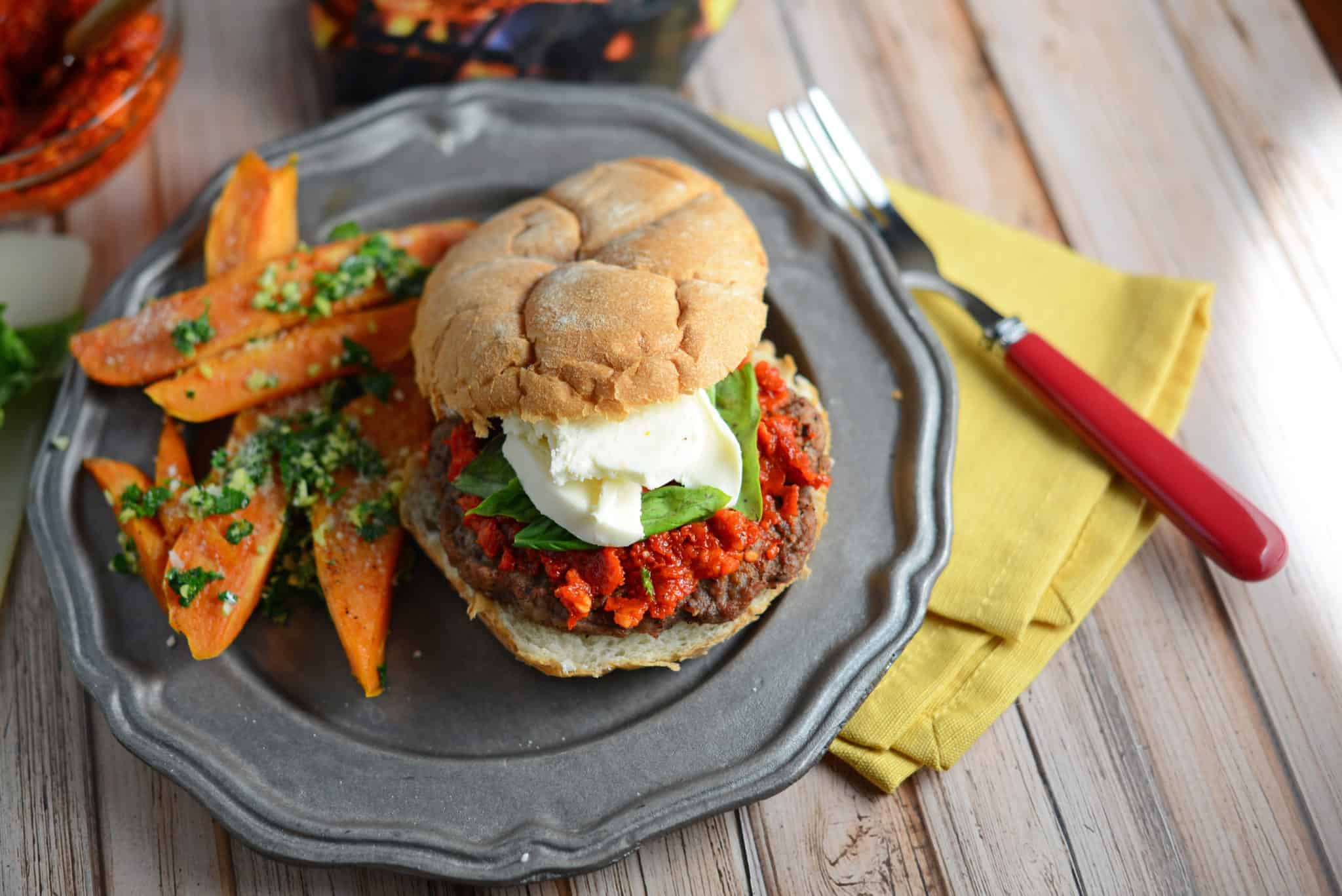 Caprese burger with sweet potato fries on a grey plate